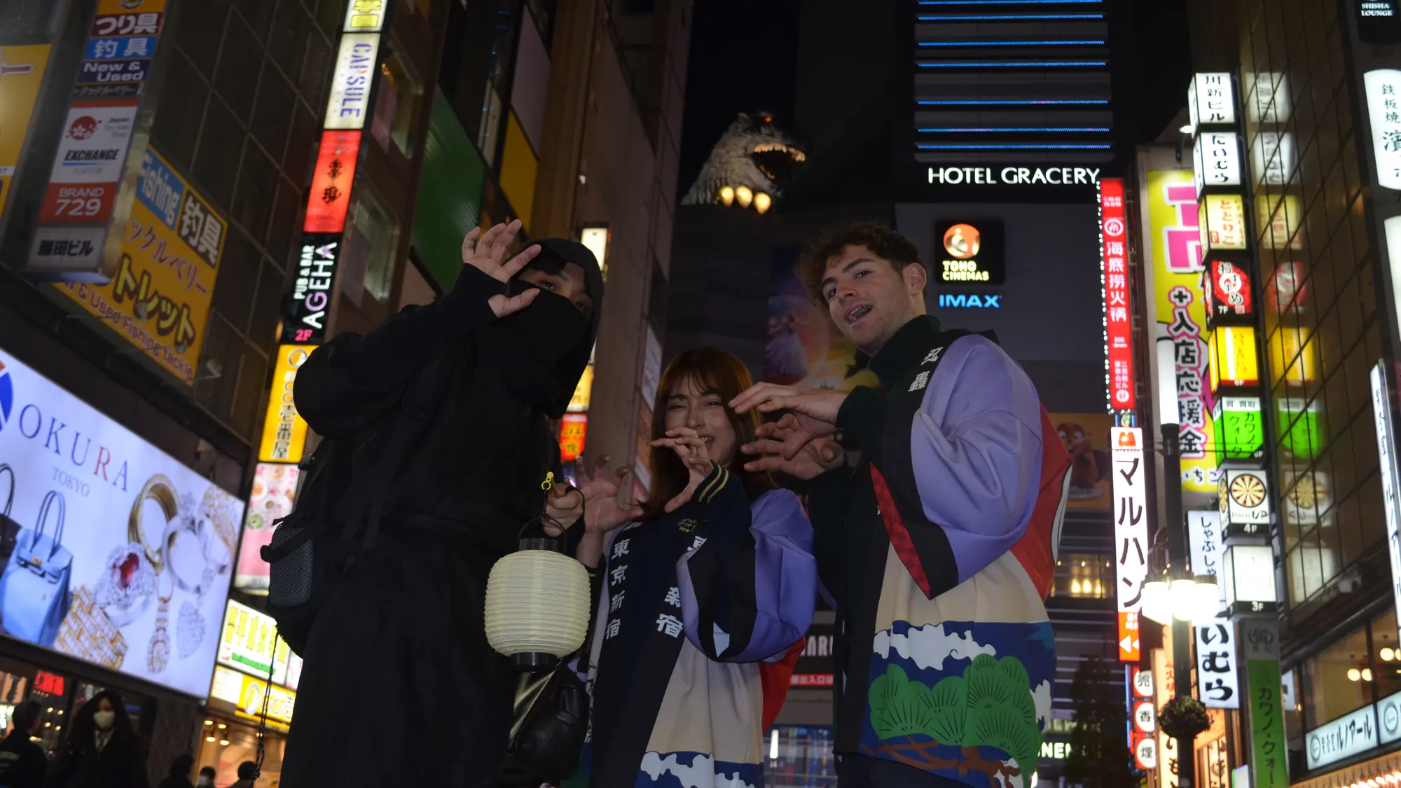 Two guests and their Ninja guide smiling under the neon of Kabukicho at night