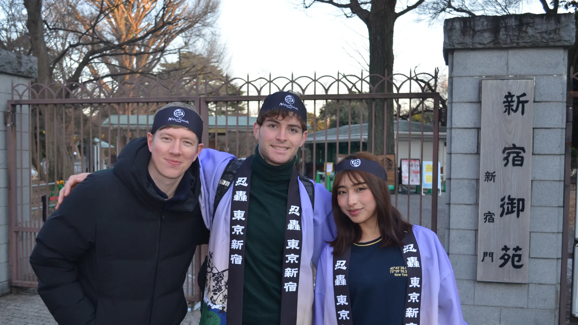 Three smiling guests with their Ninja guide at the gate of Shinjuku Gyoen