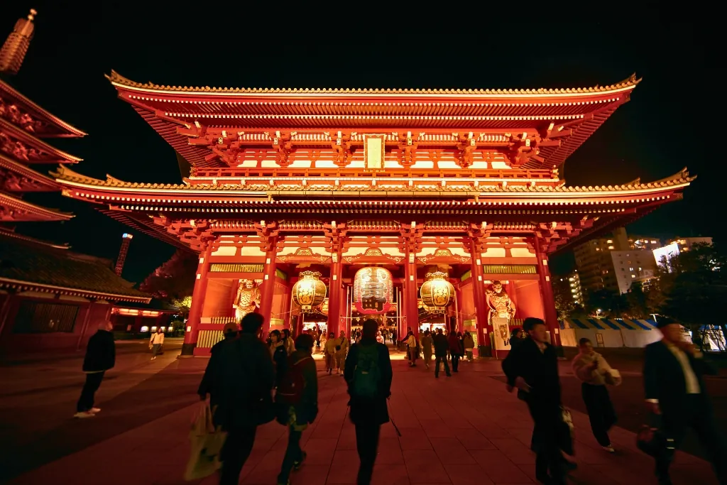 Visitors walking toward the lit-up Hozomon gate