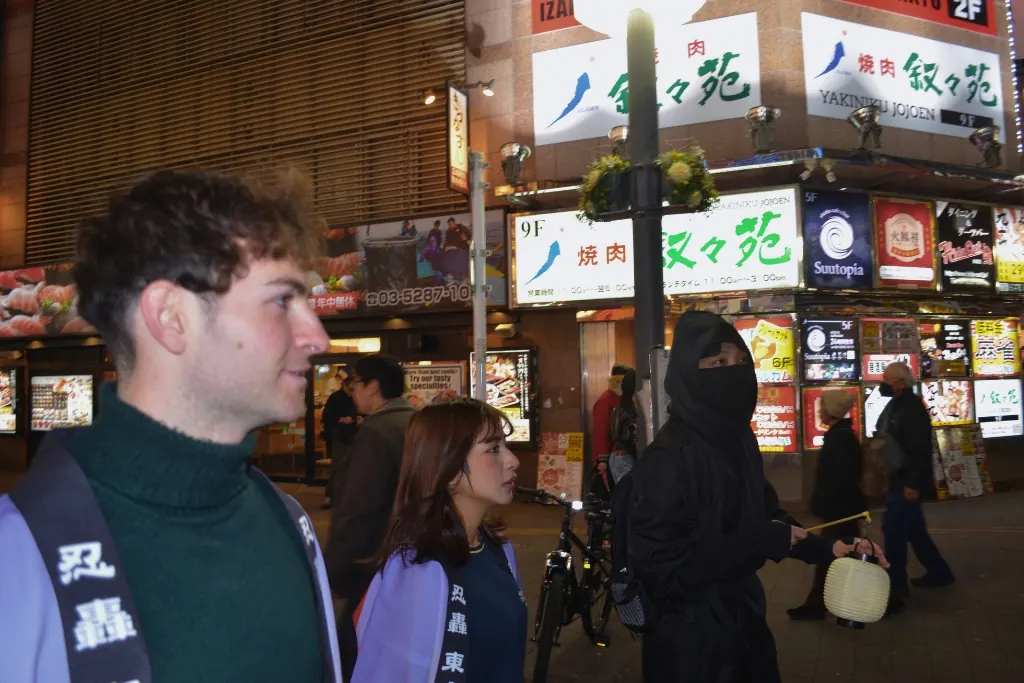 A guest smiling on a Shinjuku street at night