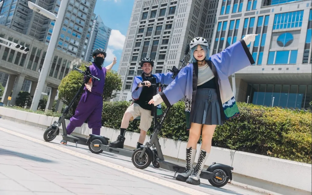 Two guests and a Ninja guide posing with e-scooters in front of Shinjuku skyscrapers