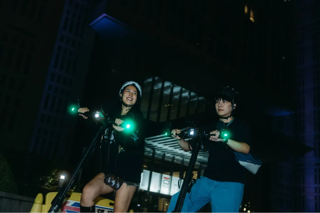 A group riding e-scooters at night