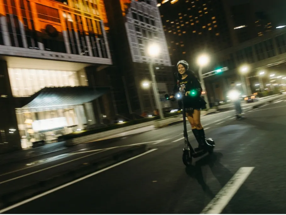E-scooter riders on a Shinjuku street at night