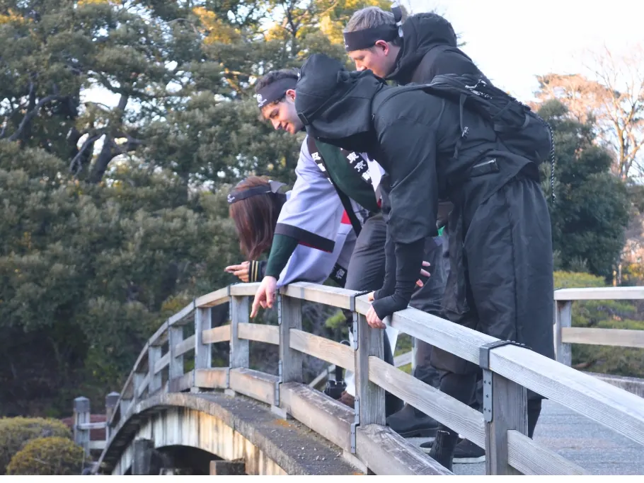 Guests crossing the red-railed bridge in the Japanese garden