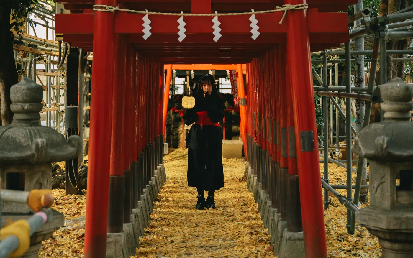 A Ninja guide standing in a tunnel of red torii gates at a hidden Shinjuku shrine