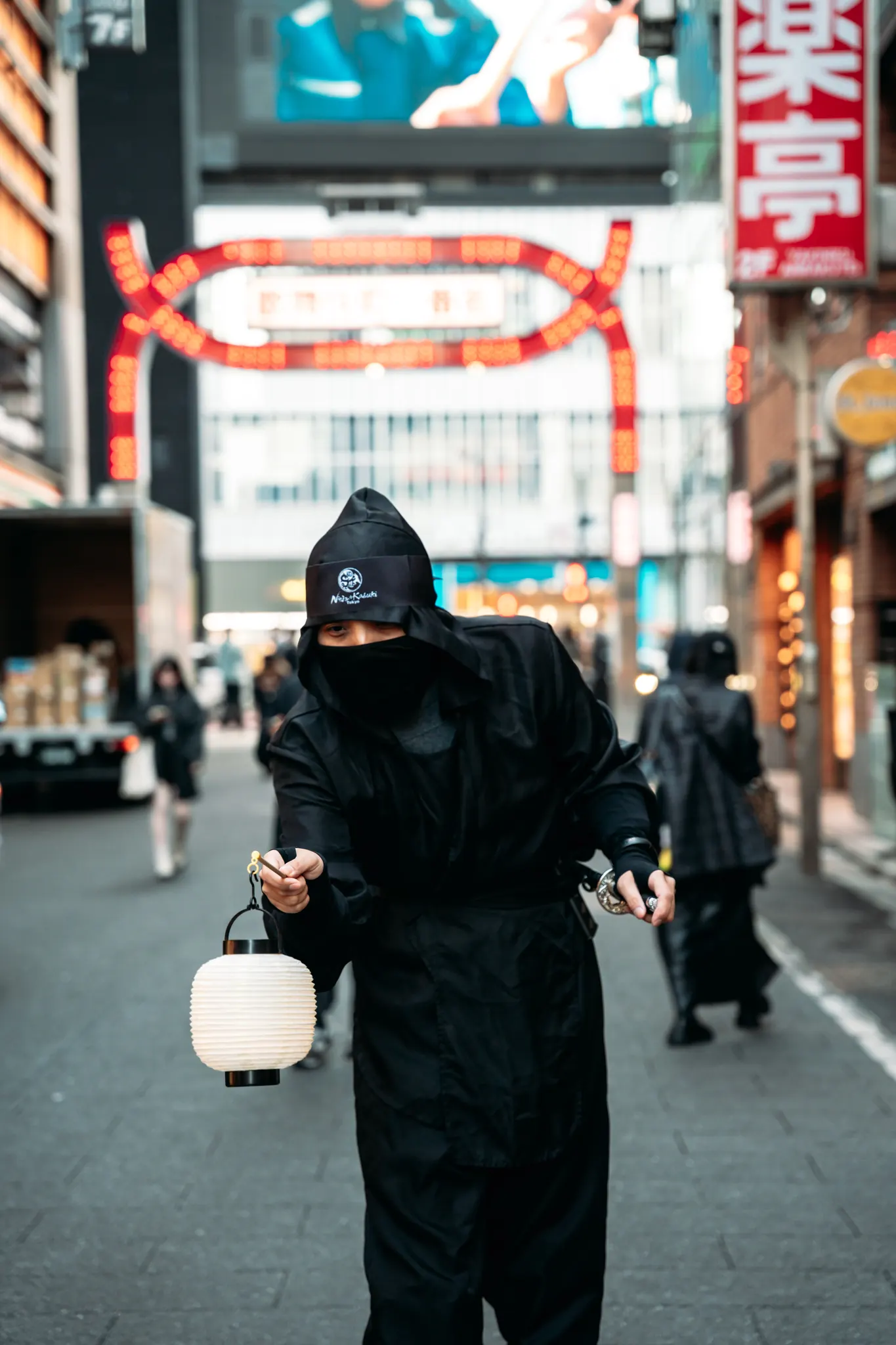 The Ninja guide holding a paper lantern on a Kabukicho street