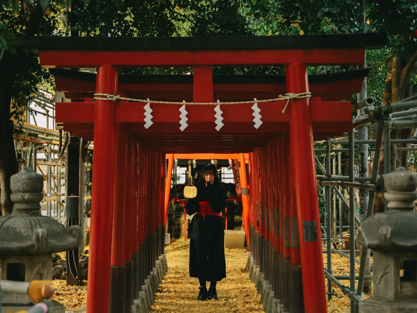 A Ninja guide with a lantern in a tunnel of red torii gates