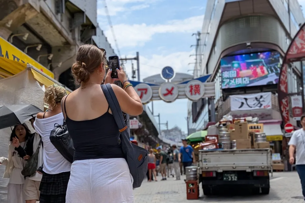 A guest taking a photo of the Ameyoko sign on Ueno’s busy market street