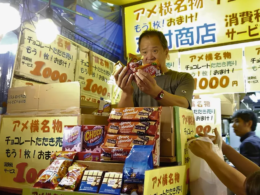 A vendor holding up snacks at a Tataki-uri street auction